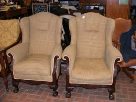 A pair of antique style wing arm chairs on carved ball and claw supports