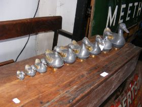 A set of nine graduated metal ducks