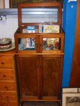 A narrow wooden cabinet with glazed upper section