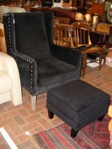 A wing lounge armchair with stool upholstered in b