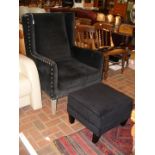 A wing lounge armchair with stool upholstered in b