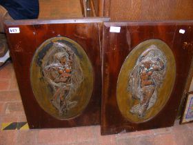 A pair of oval metal plaques of female forms in wo
