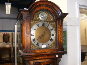 A 1920's oak long case clock with arched brass dia