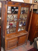 An antique oak display cabinet with cupboards belo