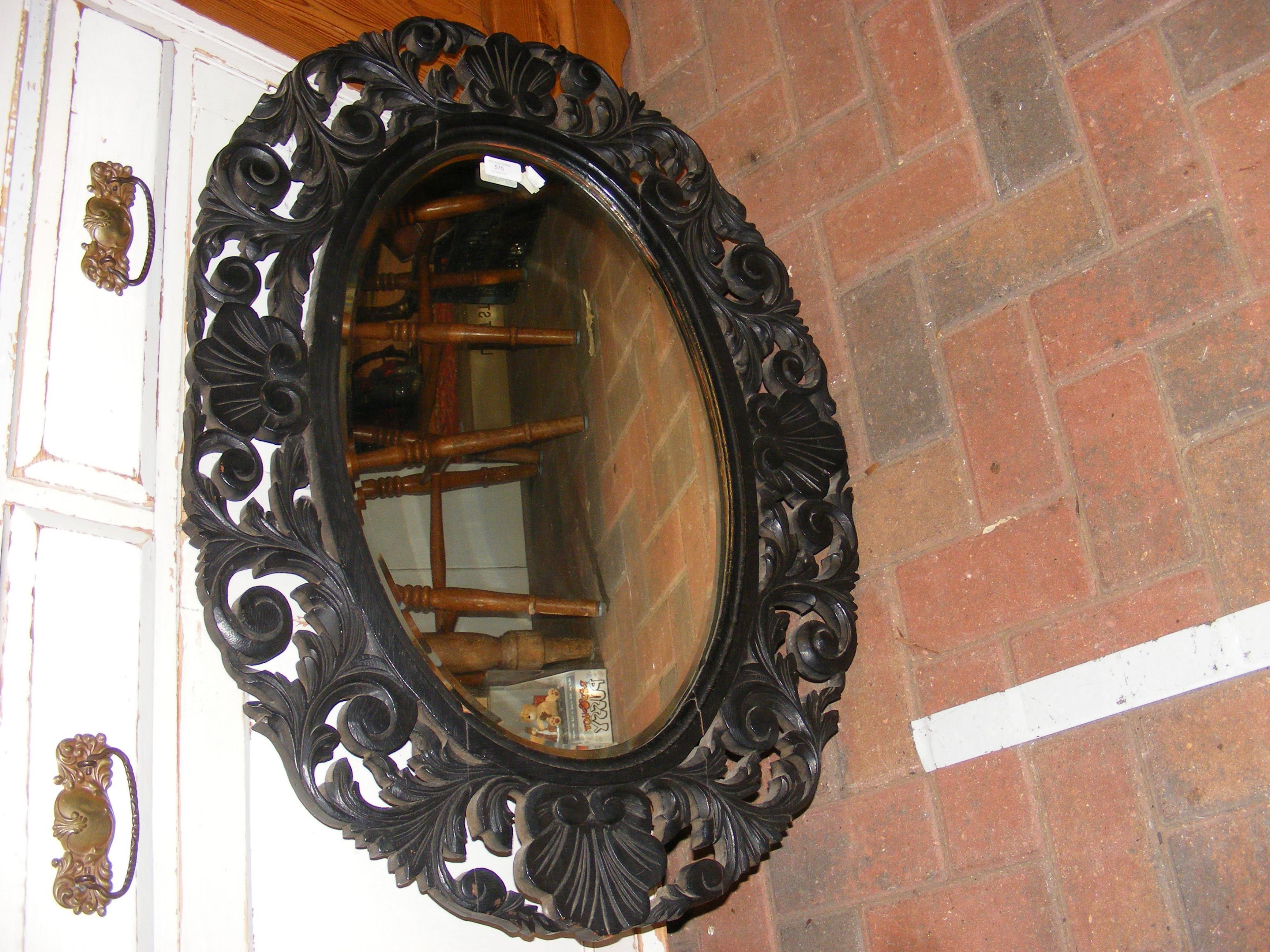 A bevelled oval mirror in ornate wooden surround