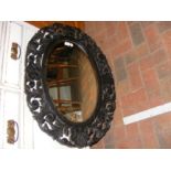 A bevelled oval mirror in ornate wooden surround