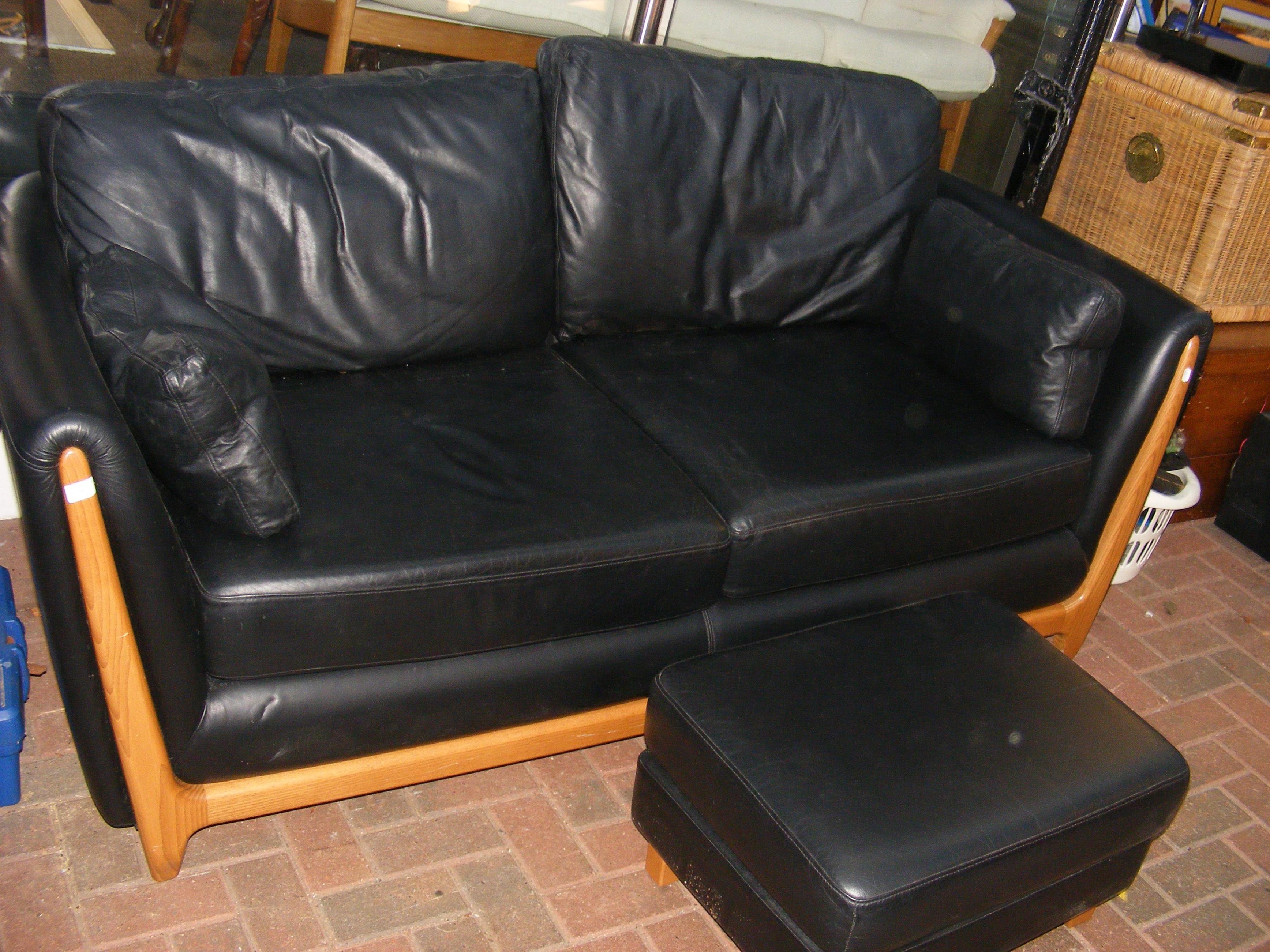 An Ercol black leather sofa with matching footstoo