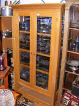 A light oak glazed bookcase with drawer below - wi