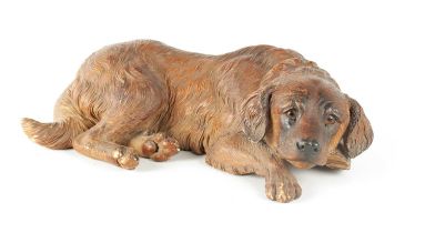 A 19TH CENTURY BLACK FOREST CARVED LINDEN WOOD FIGURE OF A RECUMBENT DOG