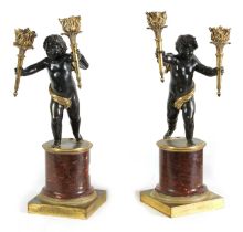 A PAIR OF EARLY 19TH CENTURY FRENCH GILT BRONZE AND ROUGE MARBLE TWO BRANCH STANDING CHERUB CANDELAB