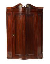 A 19TH CENTURY MAHOGANY SERPENTINE FRONTED HANGING CORNER CUPBOARD IN THE MANNER OF DUNCAN PHYFE