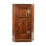 AN EARLY 18TH CENTURY OAK PANELLED HANGING CORNER CUPBOARD