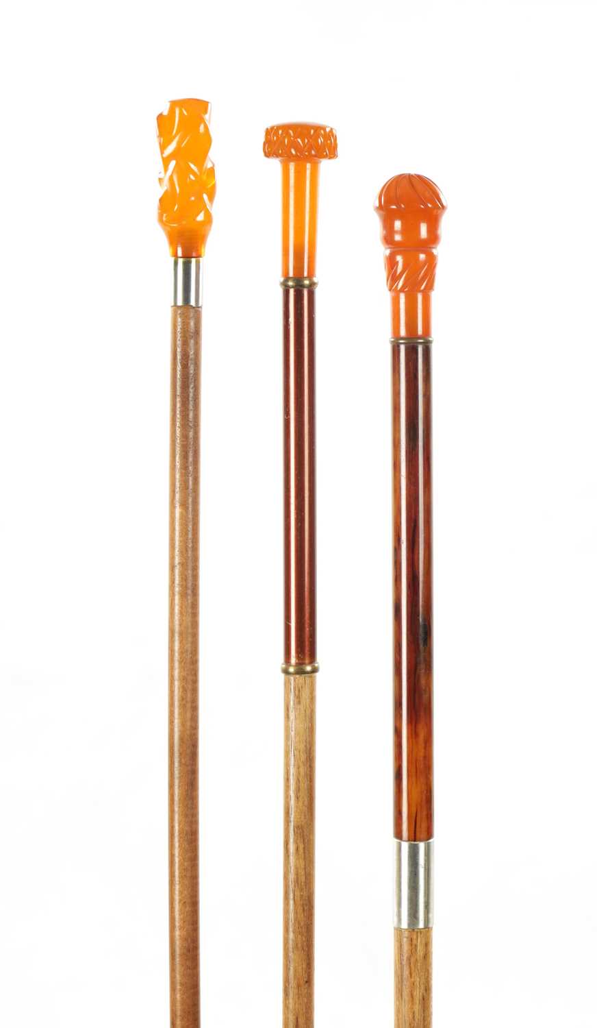 A COLLECTION OF THREE LATE 19TH CENTURY AMBER TYPE TOPPED WALKING STICKS