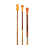 A COLLECTION OF THREE LATE 19TH CENTURY AMBER TYPE TOPPED WALKING STICKS