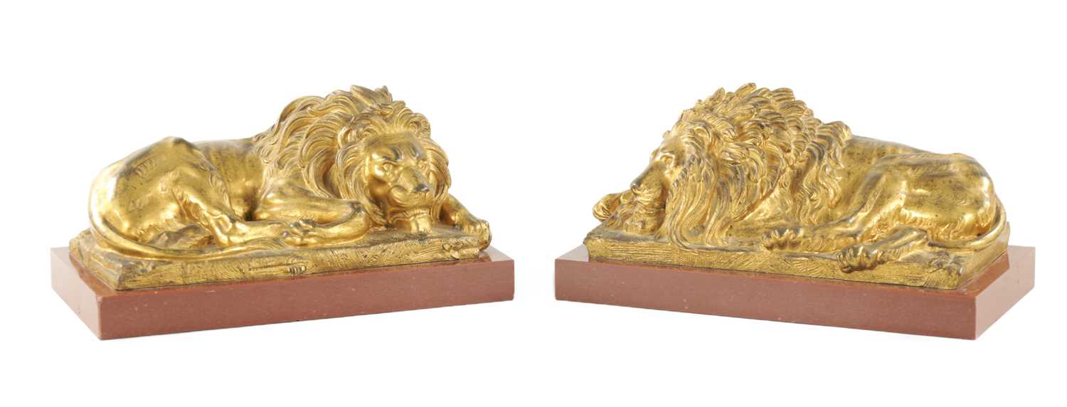 A PAIR OF LATE 19TH CENTURY GILT BRONZE RECUMBENT LIONS