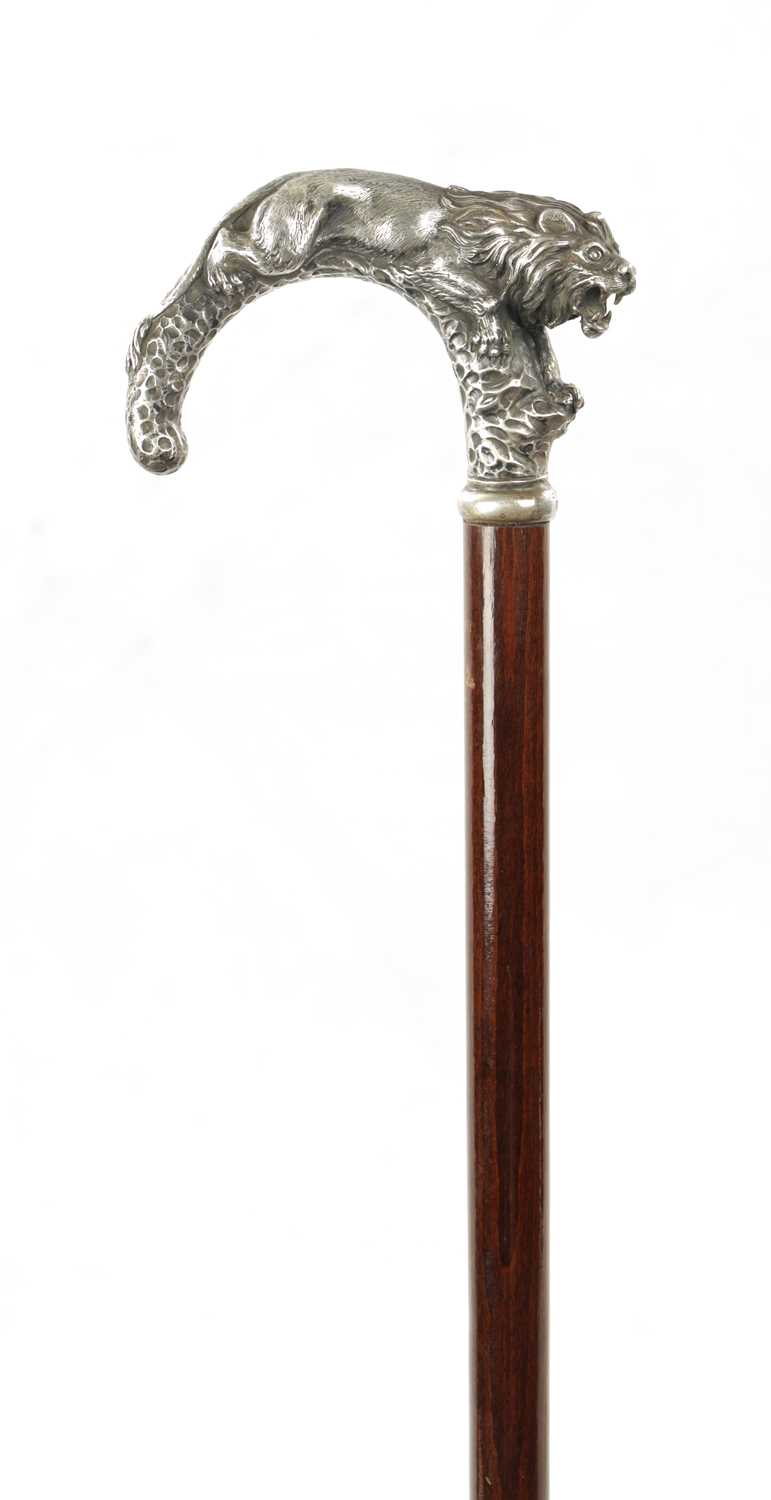 A LATE 19TH CENTURY SILVER TOPPED WALKING STICK MODELLED AS A PROWLING LION