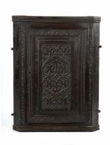 A 19TH CENTURY CARVED OAK HANGING CORNER CUPBOARD