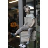 Nao figure of a Paperboy seated on stack of papers. 23cm in Height