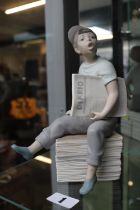 Nao figure of a Paperboy seated on stack of papers. 23cm in Height