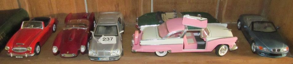 A pink Cadillac (door damaged) and five other cars