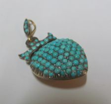 A yellow metal heart pendant with turquoise stones and turquoise bow on top