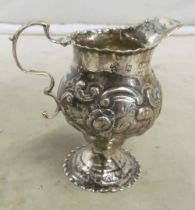 A silver cream jug with embossed decoration