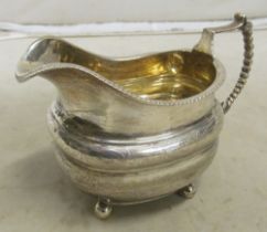 A Georgian silver milk jug engraved leaf design on bun feet 7oz