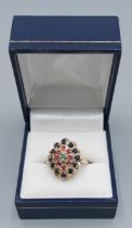 A 9ct gold cluster ring set with a central Emerald surrounded by Rubies and Sapphires, 3.7gms,