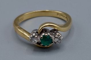 An 18ct gold Emerald and Diamond three stone ring with crossover setting, ring size K, 3.7gms