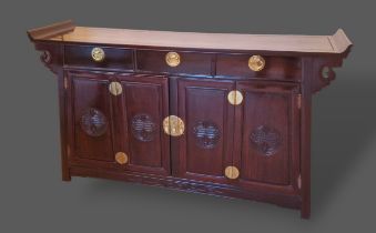 A Chinese hardwood sideboard, the shaped top above three drawers and two cupboards doors with carved