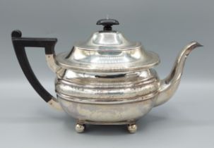 A Victorian silver teapot with engraved decoration, ebonised handle and four ball feet, London 1890,