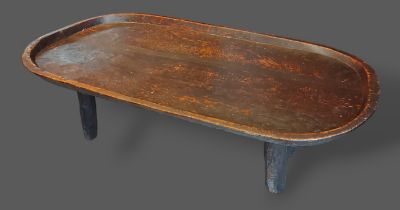 An African chip carved oval low table, the dish top raised upon low feet, 107cms by 53cms and