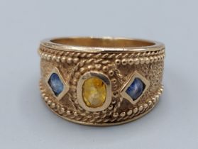 A 9ct gold dress ring set with a central Citrine flanked by Sapphire, 8gms, ring size O