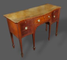 A mahogany serpentine sideboard with a central drawer flanked by cupboard doors with brass handles