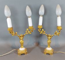 A pair of ormolu twin branch candelabra, each with figural supports, upon shaped stepped bases,