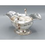 An Edwardian silver double lipped sauces boat, with twin scroll handles and raised upon a shaped