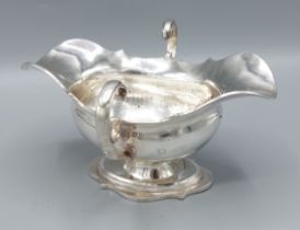 An Edwardian silver double lipped sauces boat, with twin scroll handles and raised upon a shaped