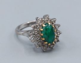 An 18ct white gold Emerald and Diamond cluster ring, with an oval Cabochon Emerald surrounded by