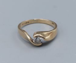 A 9ct gold solitaire diamond ring set with single diamond within a crossover setting, approx 0.15ct,