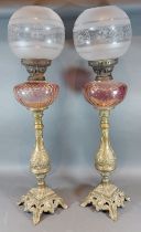 A pair of 19th Century brass oil lamps, each with a coloured glass well and etched glass shades,
