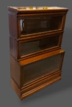 A Globe Wernicke Oak three section bookcase with glazed doors upon a shaped base, 87cms wide by