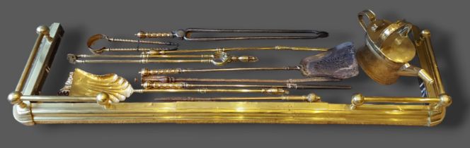 A collection of brass fire furniture to include a fender and various fire irons