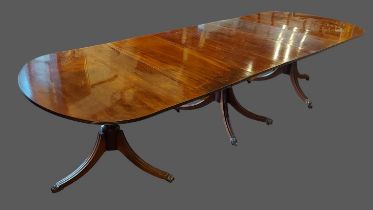A mahogany Regency style triple pillar dining table, the reeded top above outswept reeded legs