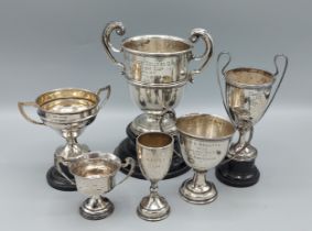 An Irish silver trophy two handled trophy cup together with five other silver trophy cups, 15ozs