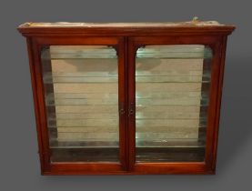 An Edwardian mahogany wall hanging shop display cabinet with two glazed doors enclosing a mirrored
