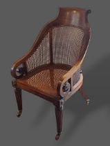 A Regency mahogany library chair, the shaped caned back with scroll arms above a caned seat raised