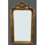 A gilded over mantle mirror with shaped cresting and foliate decorated frame, 155cms by 85cms