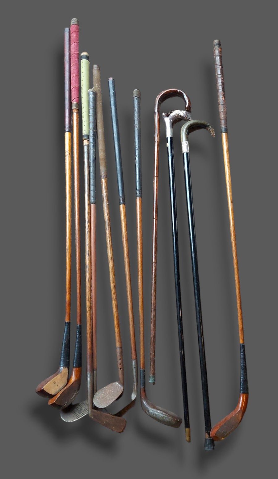 A collection of early golf clubs together with three walking canes