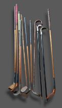 A collection of early golf clubs together with three walking canes