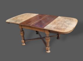 A 1930's oak drawer leaf extending dining table raised upon turned legs with stretchers, together